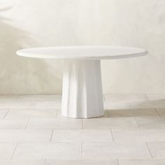 a white round table sitting on top of a tiled floor