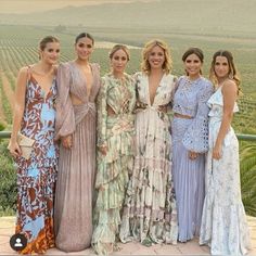 the ladies are posing for a photo together in front of some hills and vineyards