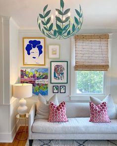 a living room filled with furniture and pictures on the wall next to a light fixture