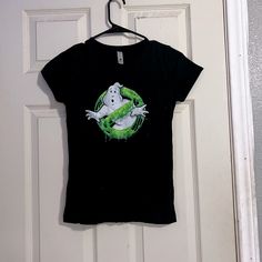 a black shirt with ghost on it hanging from a door