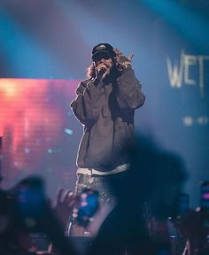 a man standing on top of a stage with his hands up to his face while holding a microphone in front of him