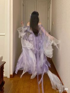 a woman in a purple dress is walking down the hall way with her arms outstretched