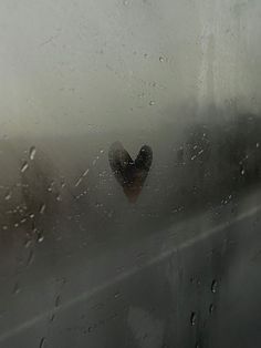 a heart shaped object sitting on top of a window covered in raindrops,