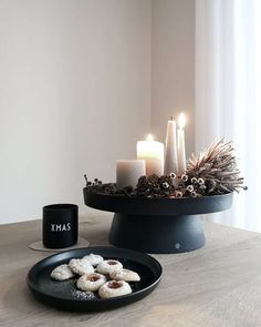 a table topped with candles and cookies on top of a wooden table next to a black plate