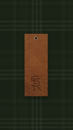 a leather tag with the letter f on it sitting on a green tarp background