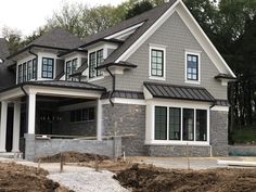 a large house is being built in the middle of some dirt and grass with trees in the background