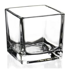 an empty glass cube sitting on top of a white table next to a black pen