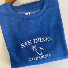 San Diego California embroidered Crewneck San Diego California with a doodle of a palm in the center on an Blue crewneck. This crew neck is very cozy and has a classic look to match any outfit. UNISEX SIZING- fits true to size. Order up for an oversized fit 80/20 cotton/polyester blend fleece Every item is made in our studio Please allow up to 7 business days for your order to ship. CARE INSTRUCTIONS: All embroidered crews and hoodies can be washed and dried on any setting, I recommend washing w Blue Embroidered Crew T-shirt, Blue Crew T-shirt With Custom Embroidery, Blue Crew Neck T-shirt With Custom Embroidery, California Sweater, California Sweatshirt, Blue Crewneck, Embroidered Crewneck, San Diego California, Classic Looks