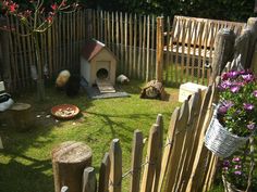 a dog house in the back yard next to a fence and flower potted plant