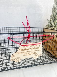 a metal basket with a sign attached to it sitting next to a potted plant