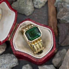 This captivating ring is centered with one (1) emerald cut natural green tourmaline set into a bezel setting. The ring is decorated with rope and beaded details. The ring measures 11.9mm at the top, rises 6.8mm above the finger, tapering to 8.2mm wide and 2.2mm thick at the base of the shank. Signed ©Dana B. This ring is currently a size 6. The tourmaline shows moderate scratches and abrasions. Yellow Gold Tourmaline Emerald-cut Ring, Green Art Deco Jewelry With Bezel Setting, Formal Emerald Cut Tourmaline Jewelry, Art Deco Green Jewelry With Bezel Setting, Yellow Gold Tourmaline Jewelry In Emerald Cut, Brand Presentation, Bezel Ring, One 1, Green Tourmaline