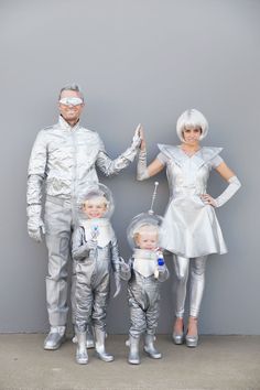 a man and two women are dressed up as astronauts with their son, who is holding an umbrella