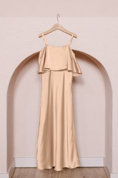 a dress hanging on a hanger in front of a wall with an arched doorway