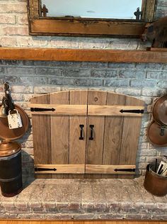 a wooden cabinet sitting on top of a brick wall next to a mirror and trash can