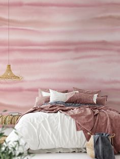 a bedroom with pink and white walls, a bed covered in blankets and throw pillows