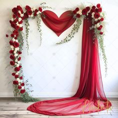 a red and white wedding arch decorated with flowers, greenery and hearts on the wall