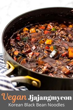 a pot filled with black bean noodle soup on top of a blue and white towel