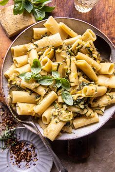 pasta with pesto and parsley in a bowl next to a glass of wine