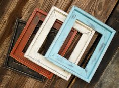 three different colored frames sitting next to each other on a wooden surface with one missing