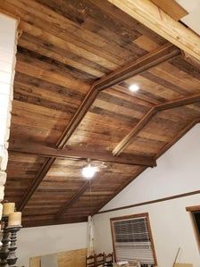 an unfinished ceiling with wooden beams and lights