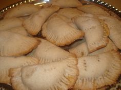 a plate full of baked pastries sitting on top of a wooden table next to a knife and fork