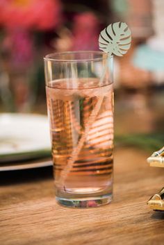 a glass filled with liquid sitting on top of a wooden table next to a plate