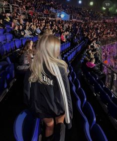 a woman standing in front of an audience at a concert with her back to the camera