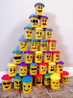 a stack of buckets with faces painted on them sitting in front of a wall