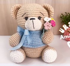 a crocheted teddy bear with a flower in it's mouth sitting on a table