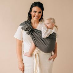 a woman holding a baby in a grey wrap