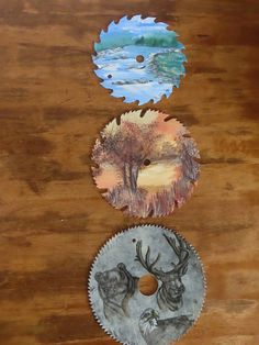 three different designs on the side of a wooden table with two circular discs in front of them