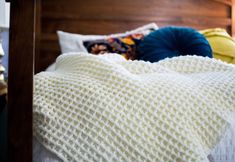 a white blanket on top of a bed next to pillows