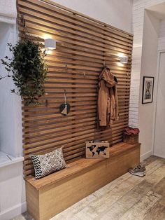 a wooden bench sitting in front of a wall mounted planter and coat hanger