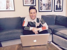 a man sitting on top of a couch with a laptop computer in front of him