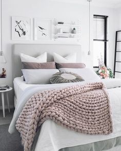 a white bed topped with lots of pillows and blankets