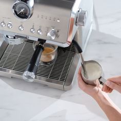 a person is using a coffee maker on a counter