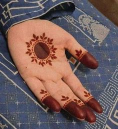 a person's hand with henna on it and an orange circle painted on the palm