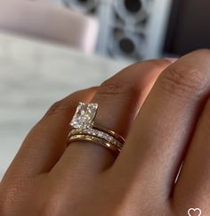 a woman's hand with a diamond ring on top of her finger and the other hand holding an engagement ring