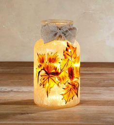 a glass jar filled with yellow flowers on top of a wooden table next to a wall