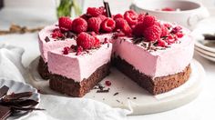 a cake with raspberries on top is cut in half and ready to be eaten