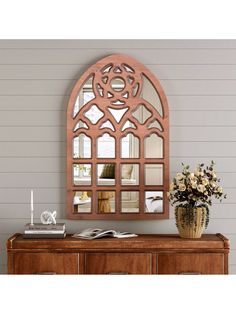 a large mirror sitting on top of a wooden dresser next to a vase with flowers