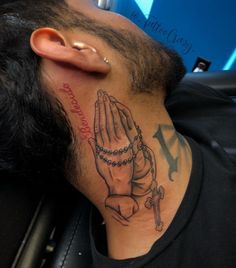 a man with a tattoo on his neck has a rosary and praying hands behind him