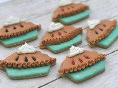 several decorated cookies with frosting and icing in the shape of pies on a table