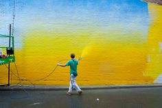 a man spray painting a yellow and blue wall