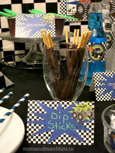 a table topped with cups and plates filled with chocolate covered straws next to paper napkins