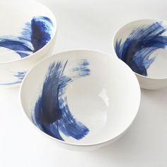 three blue and white bowls sitting next to each other on top of a white table