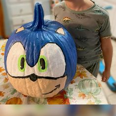 a young boy standing next to a large pumpkin shaped like sonic the hedgehog with green eyes