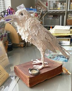 a sculpture of a bird on top of a book