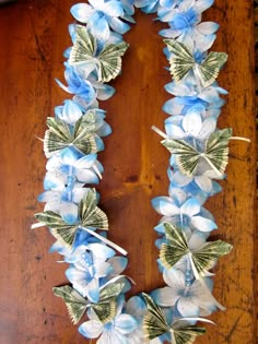 a wreath made out of dollar bills and blue flowers on a wooden table with scissors