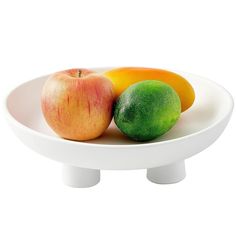 a white bowl filled with fruit sitting on top of a table next to an apple